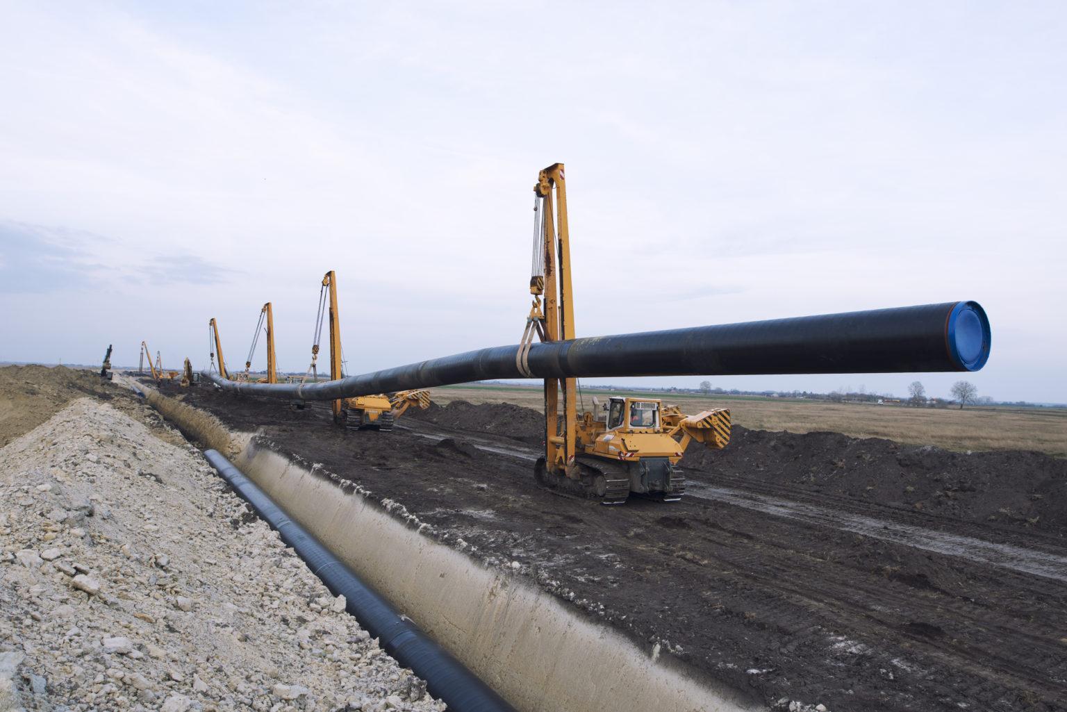 Heavy duty construction machines carrying and placing gas pipe into the ground.